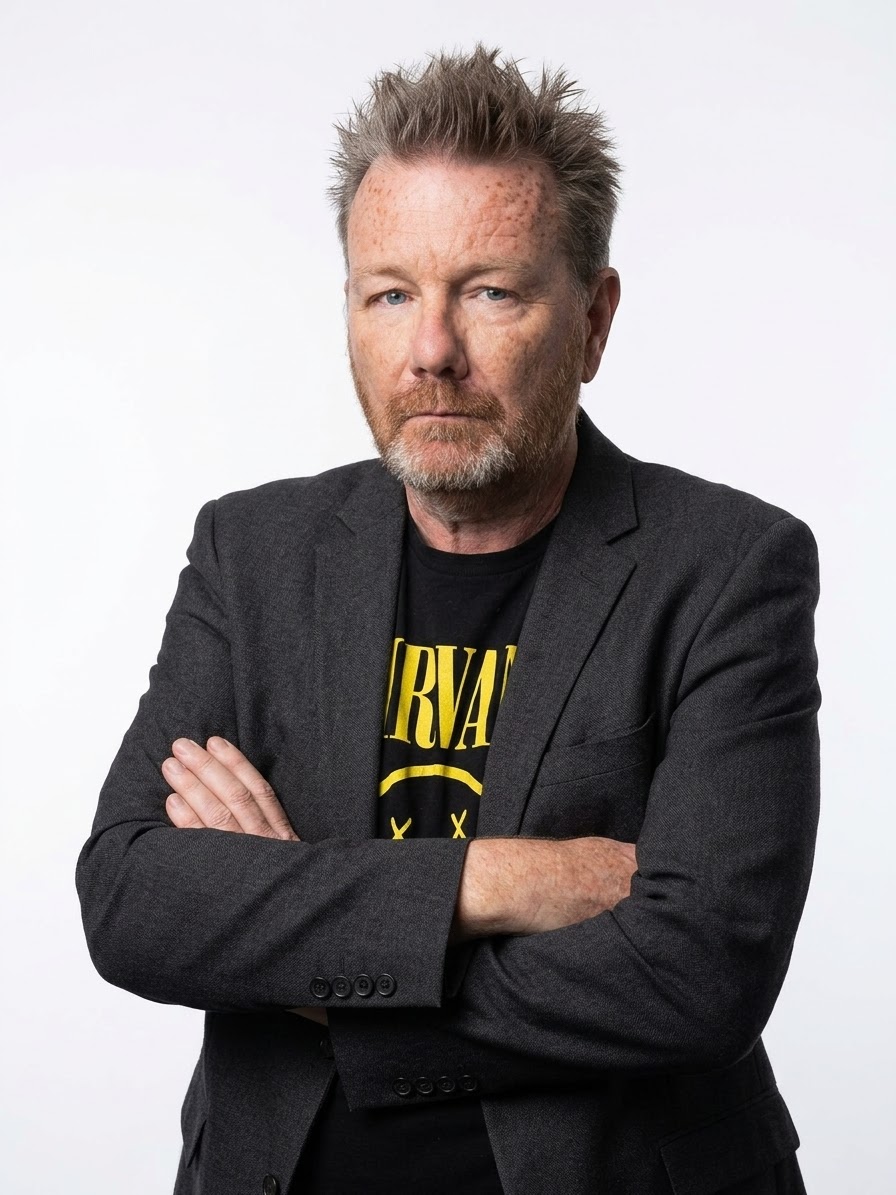 Hen D. in a blazer over a band T-shirt, arms folded