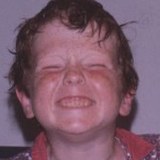 Claude, our Webmaster: a small boy with wet hair grinning with his eyes screwed shut